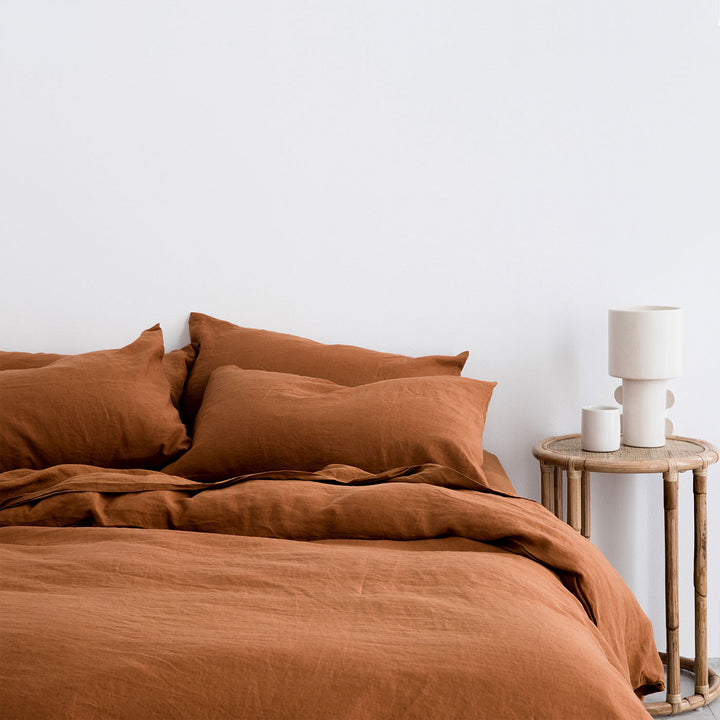 A bed dressed in Cedar bedlinen, styled with a natural side table, and white vessels.