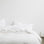 Bed styled with White Linen Duvet Cover Set and White Linen Sheet Set. On the bedside table there is a simple white vase. Sizes: Queen, King