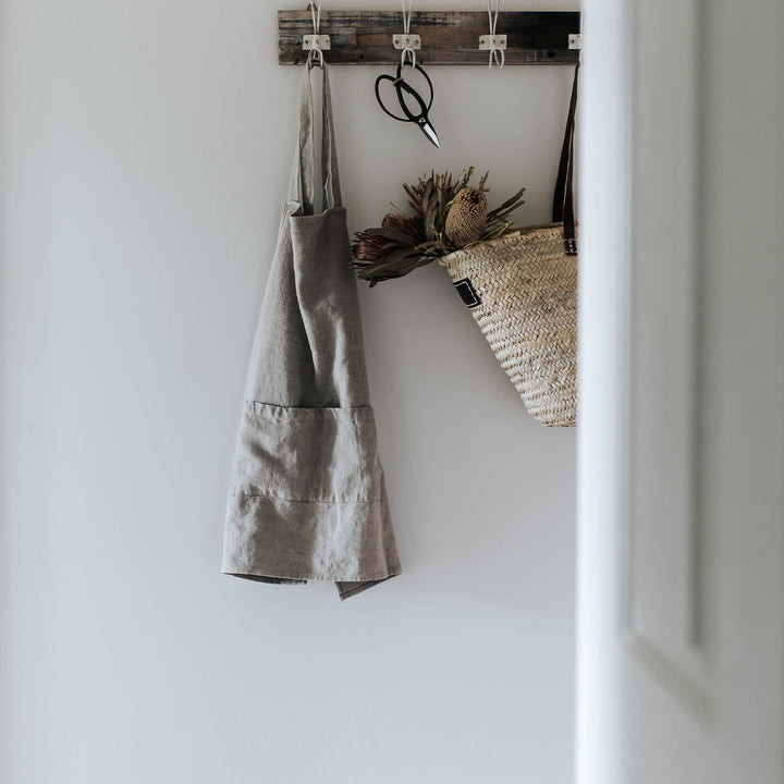 Jude Linen Apron in Natural color hangs on wall