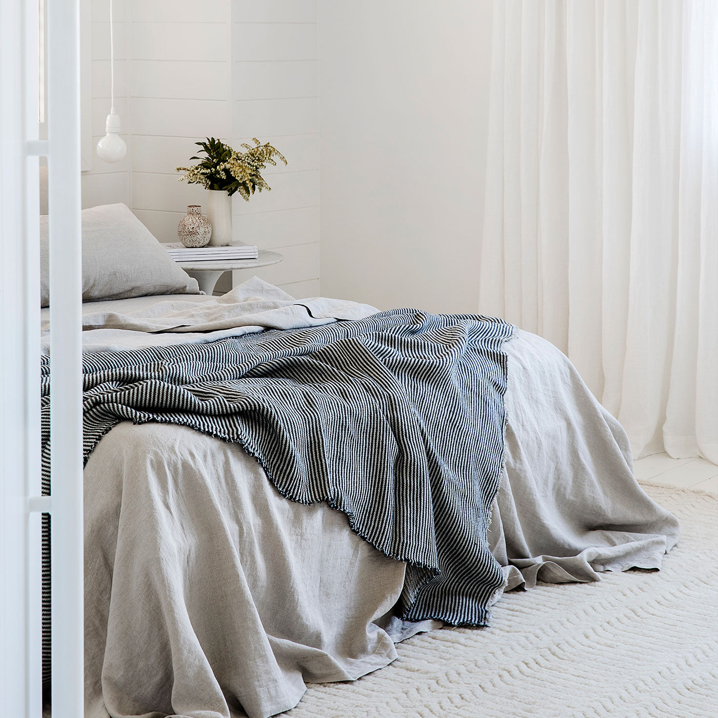 A bed styled with the Mira Linen Throw in Ellis Stripe