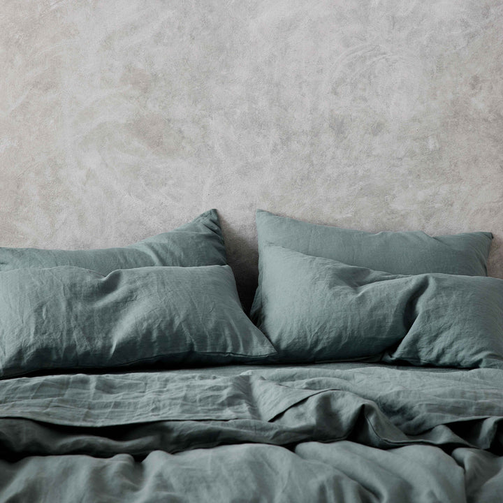 Set of 2 Linen Pillowcases, a Duvet Cover Set and Sheet Set in Bluestone on a bed.