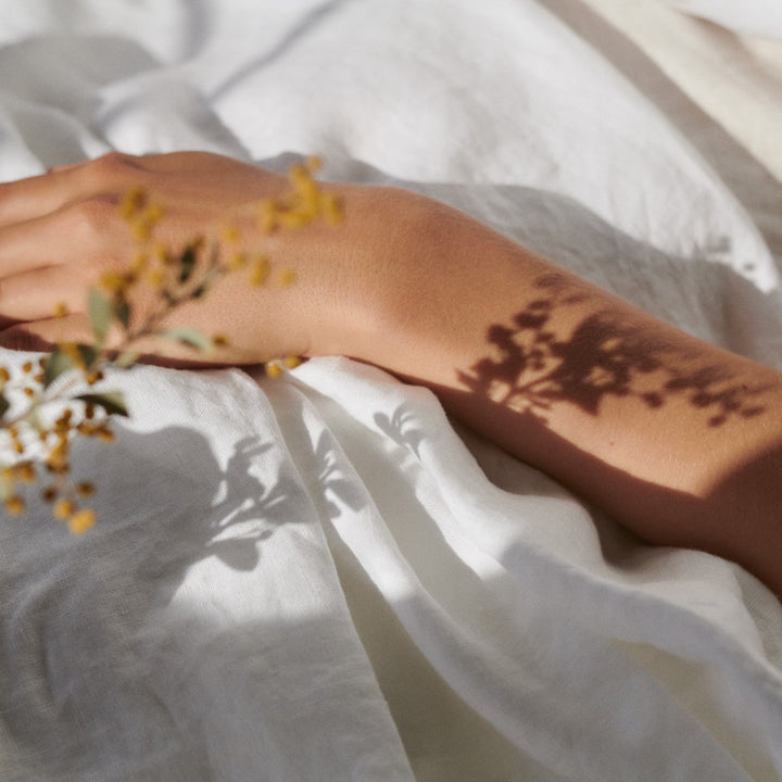 A hand resting on White bed linen